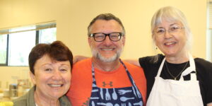 Three people standing next to each other in a kitchen.