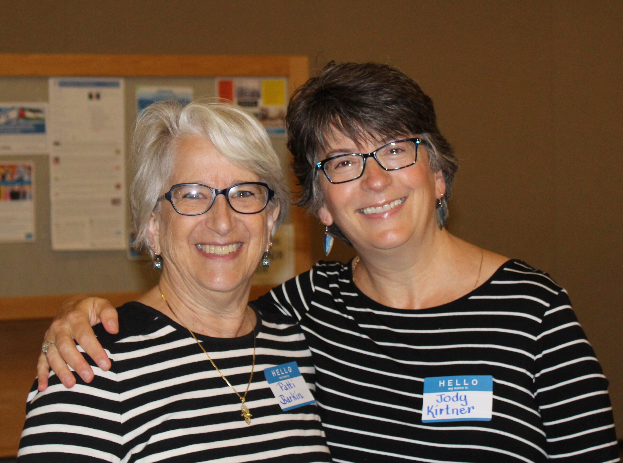 Two women standing next to each other smiling.