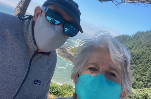 A man and woman wearing masks standing on top of a hill.