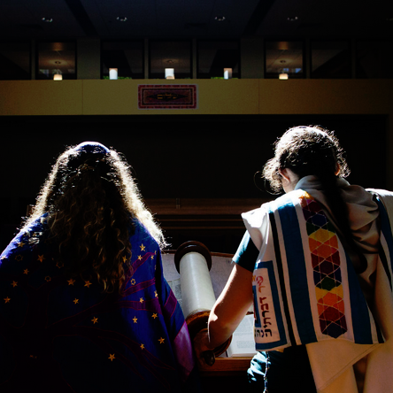 Two women holding hands in a room with lights.