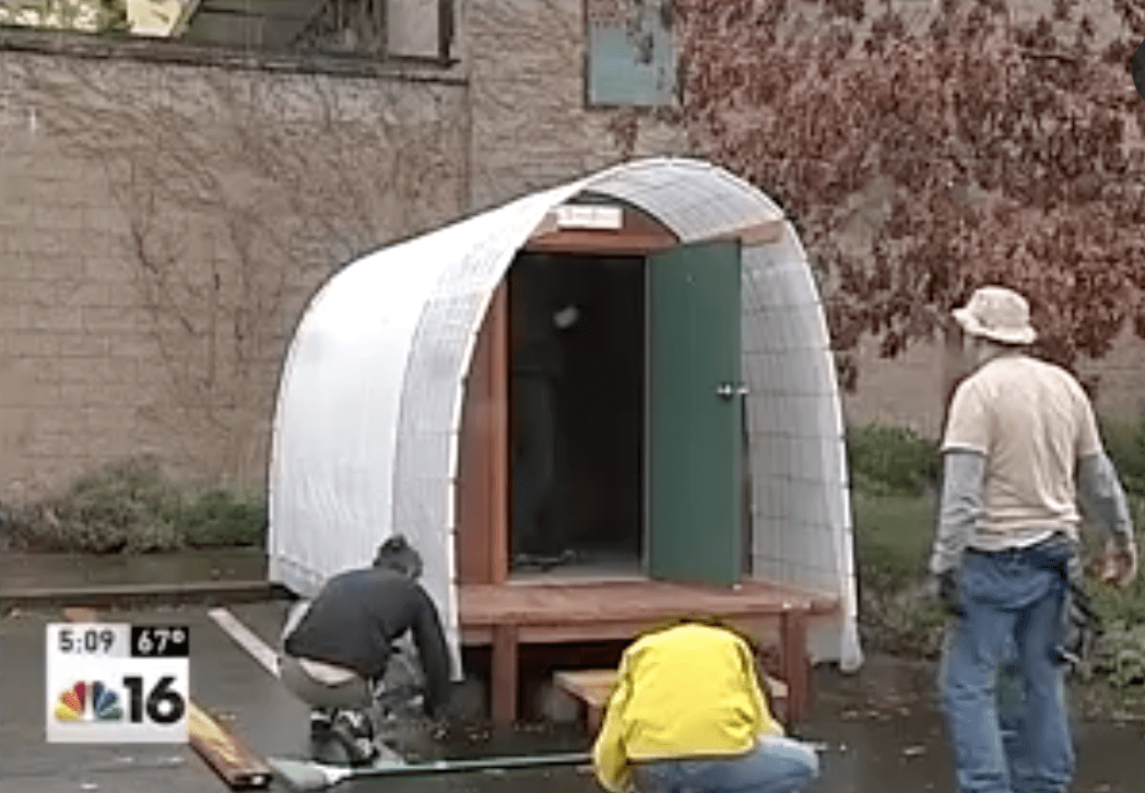 A group of men are working on a portable toilet.
