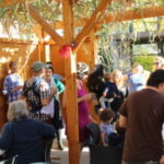 A group of people gathered around tables in a garden.