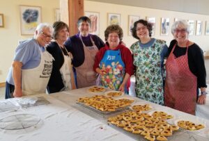 A group of people standing around a table with food.