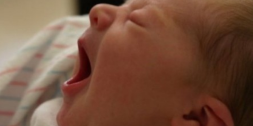 A baby is laying down and sleeping with its mouth open.