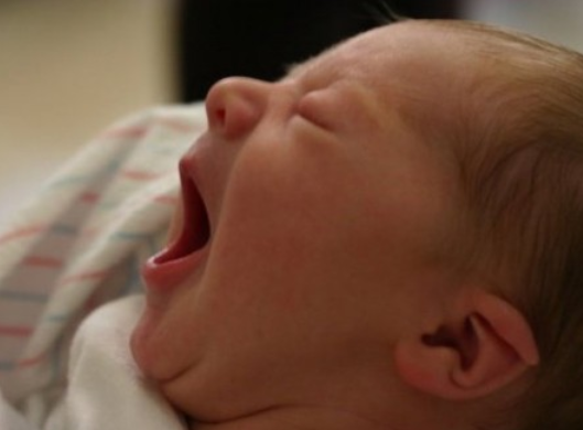 A baby is laying down and sleeping with its mouth open.