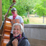 A man standing next to another man holding a cello.