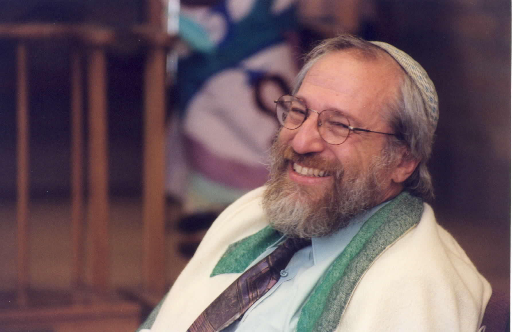 A man with a beard and glasses sitting in a chair.