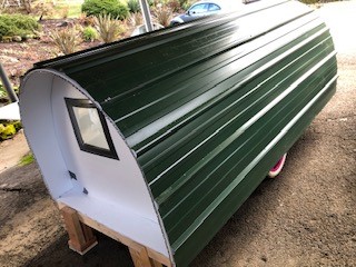 A green and white trailer is parked on the ground.