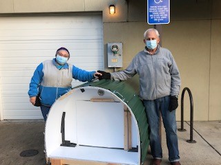 Two people wearing masks standing next to a large object.