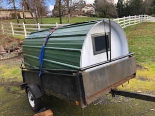 A small trailer with a green roof and window.