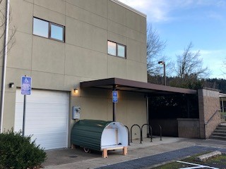 A green and white barrel sitting in front of a building.