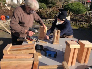 Two people building wooden blocks on a table.