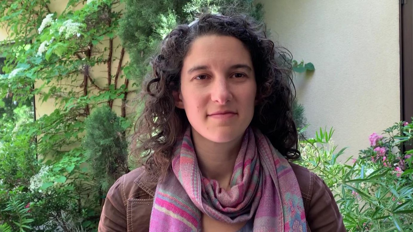 A woman with curly hair wearing a scarf.