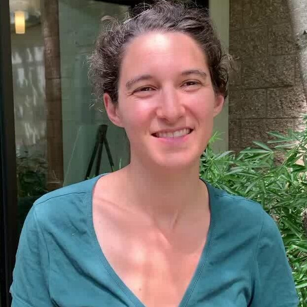 A woman in a blue shirt smiling for the camera.