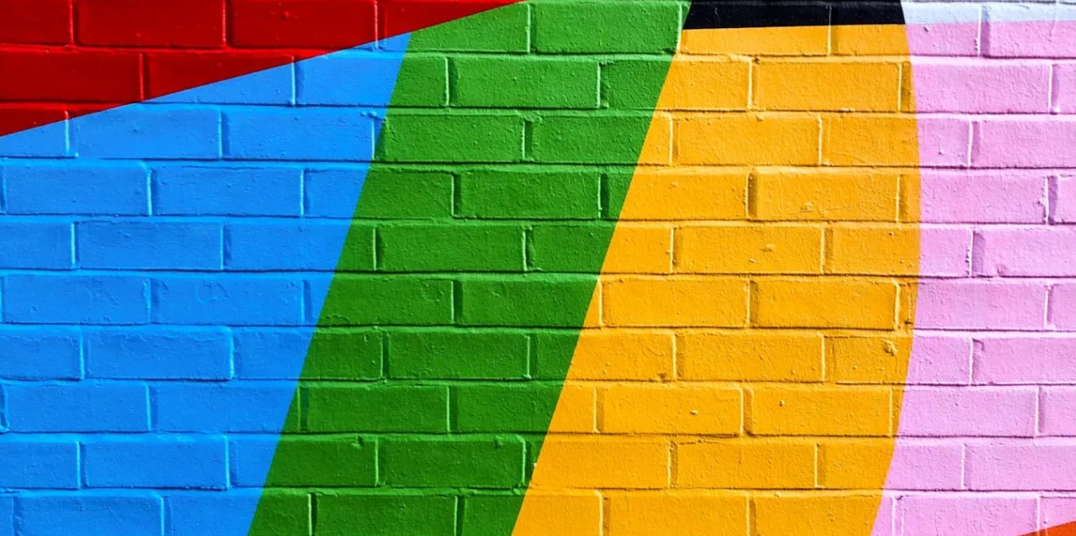 A brick wall with different colors painted on it.