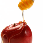 A close up of an apple with honey being poured on it