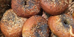 A pile of bagels covered in sesame seeds.