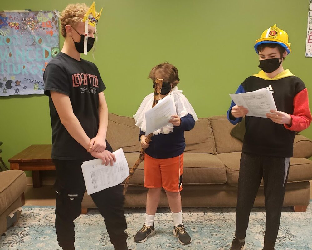 Three people standing in a living room wearing masks.