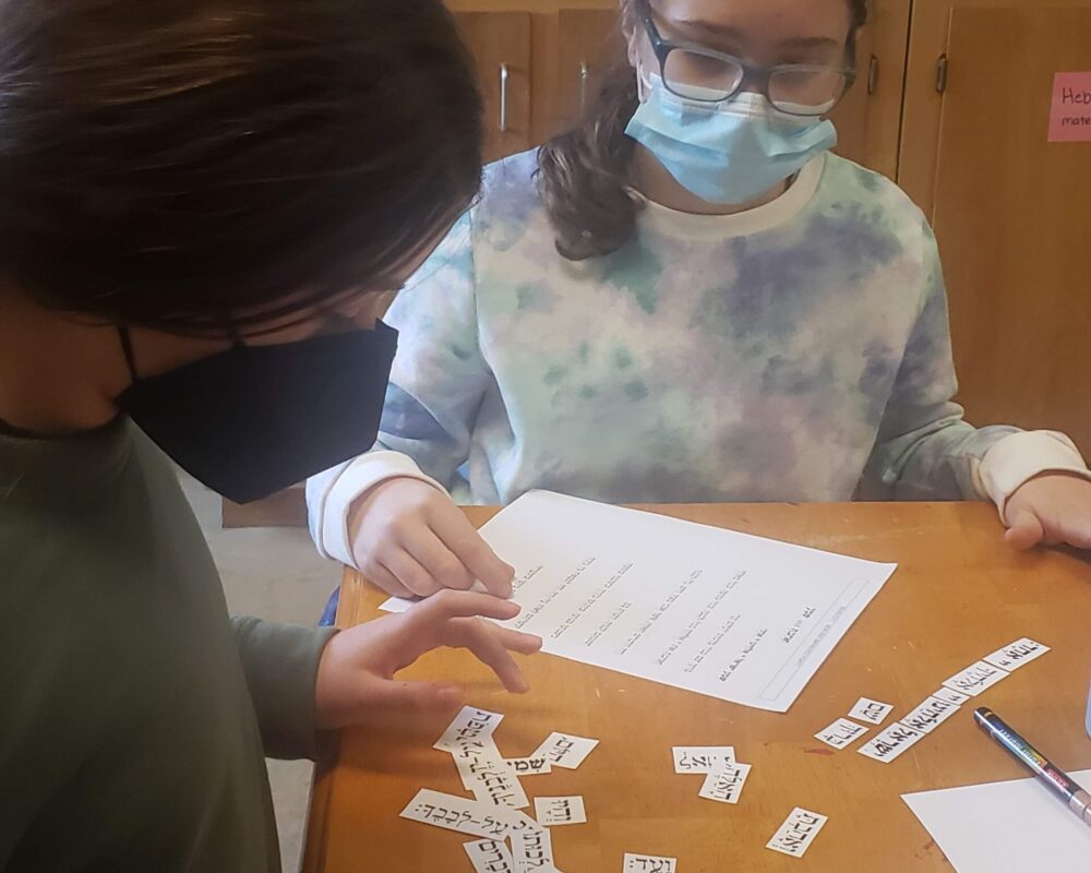 Two people sitting at a table with papers and masks on