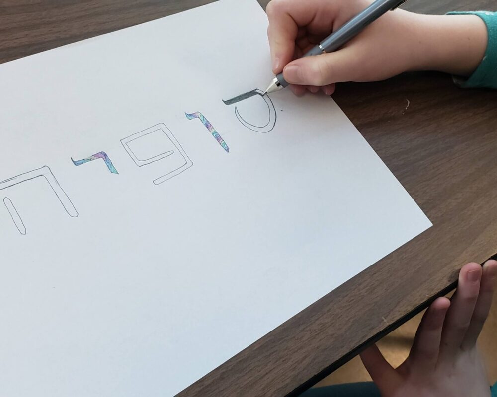 A person is drawing numbers on paper with a pair of scissors.