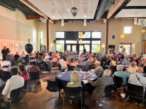 A large group of people sitting at tables in a room.