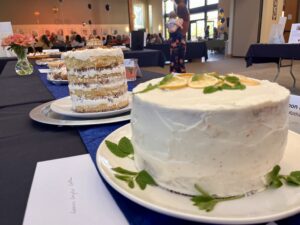 A table with several cakes on plates and one cake is sitting in front of the other.