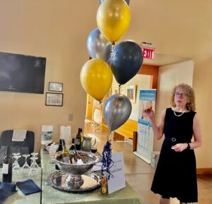 A woman standing next to balloons and a table.