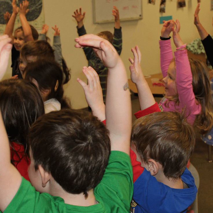 A group of children raising their hands in the air.